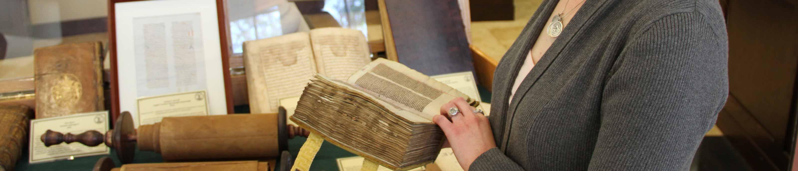 学生 examining an old tome during the Wisdom of the Ages exhibit